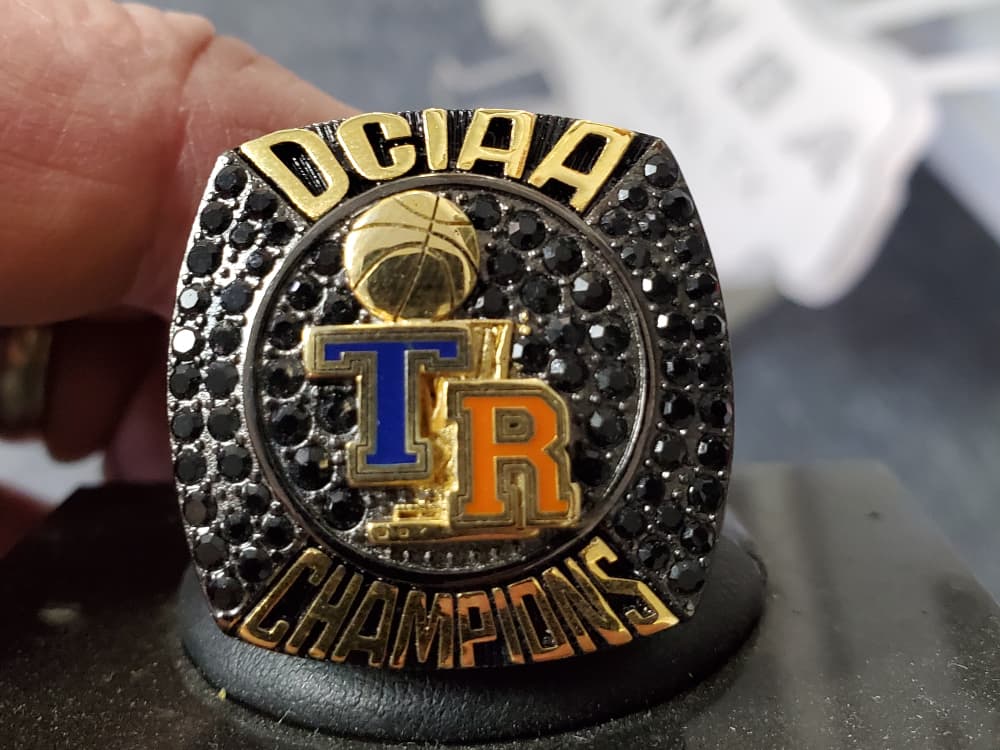 Custom basketball championship ring with black stone pave held in hand